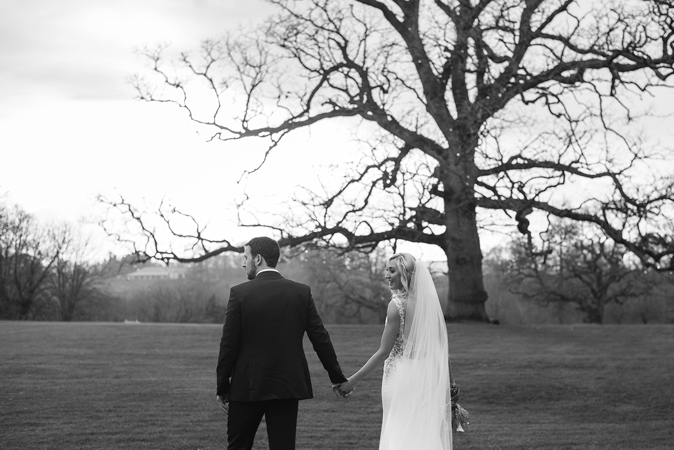 bride and groom walk to rathsallagh tree black and white wedding photo