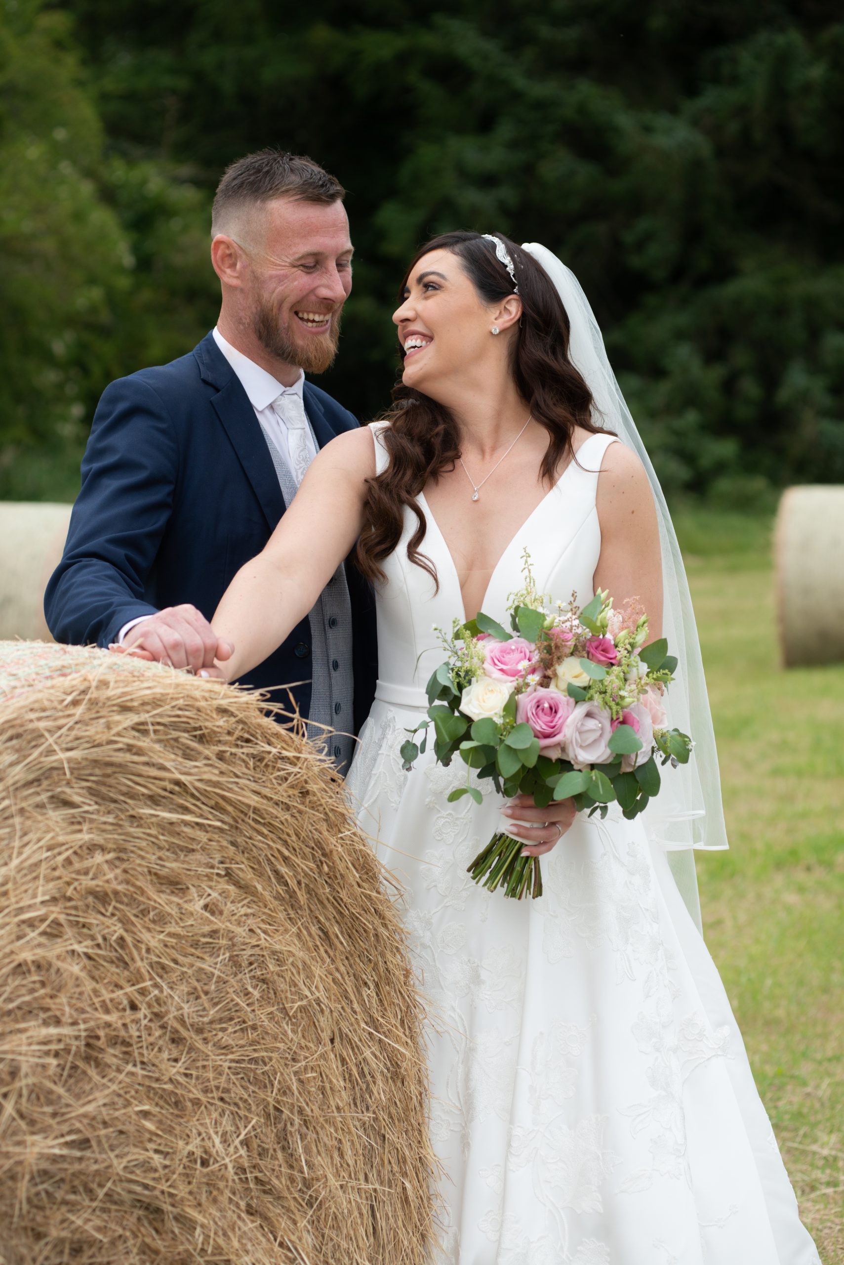 Couple smiling by bale of hay
