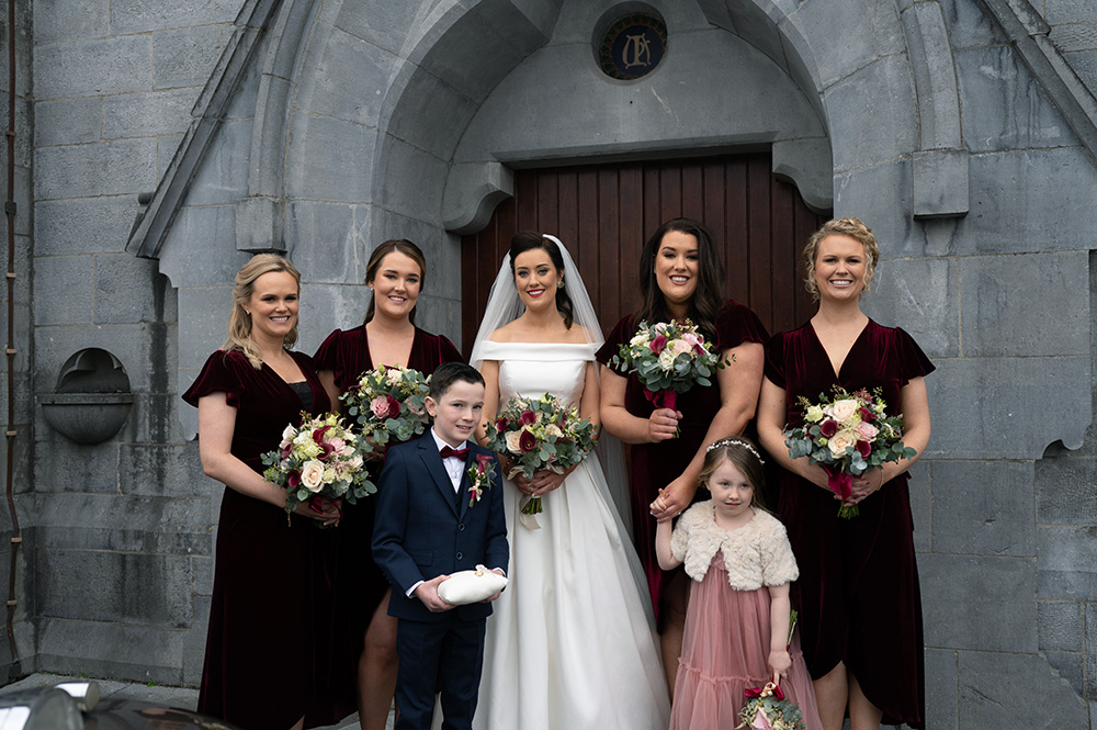 Bride and bridesmaids standing outside chapel