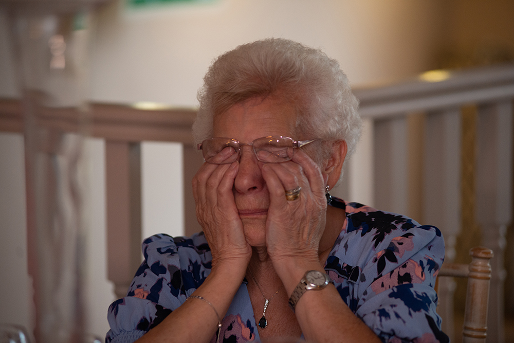 Elderly lady wiping her eyes
