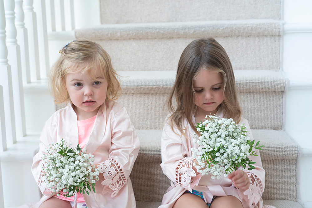 Two little girls sitting on stairs holding bouquets