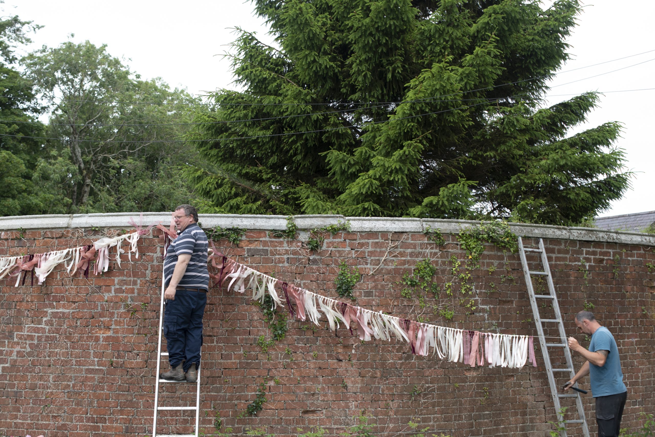 Men hanging up pink and white garland outside