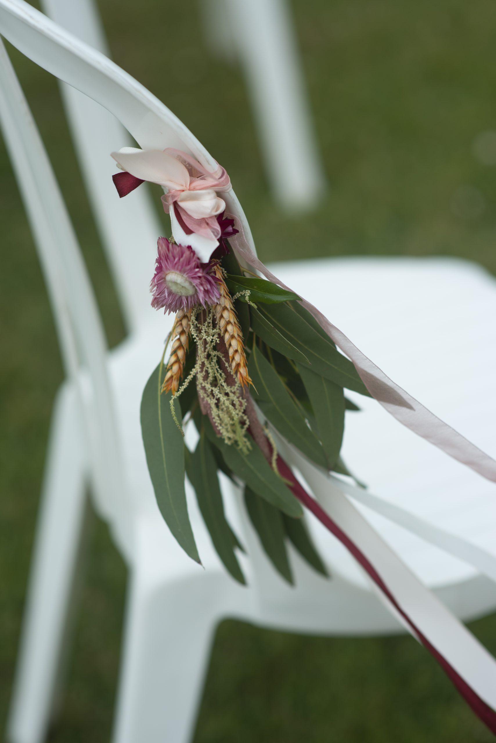 close up flowers tied to white chair