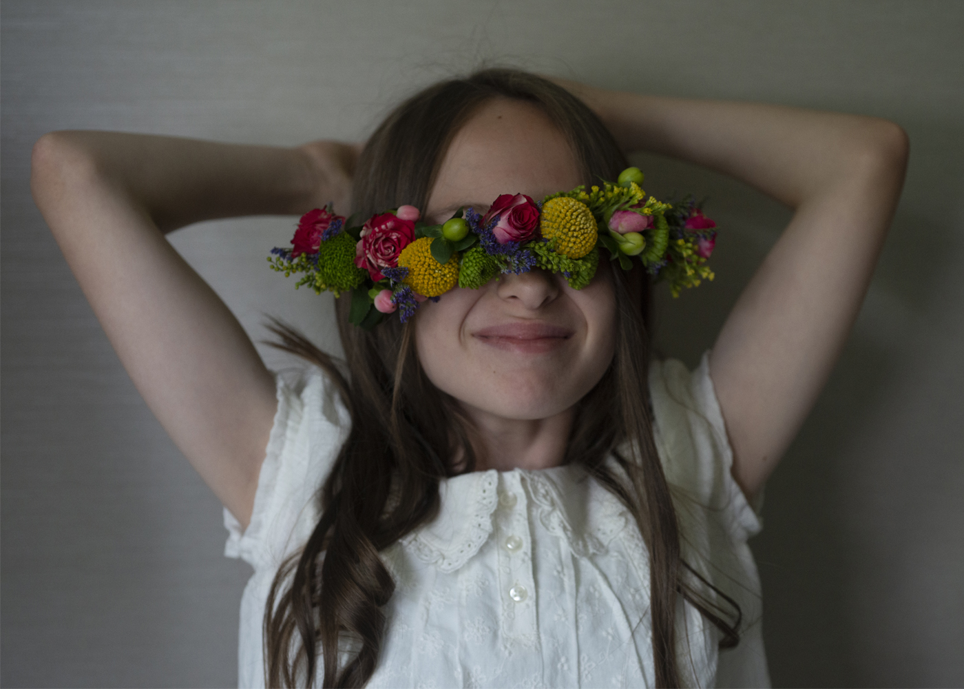 young girl smiling with flower crown in front of her eyes